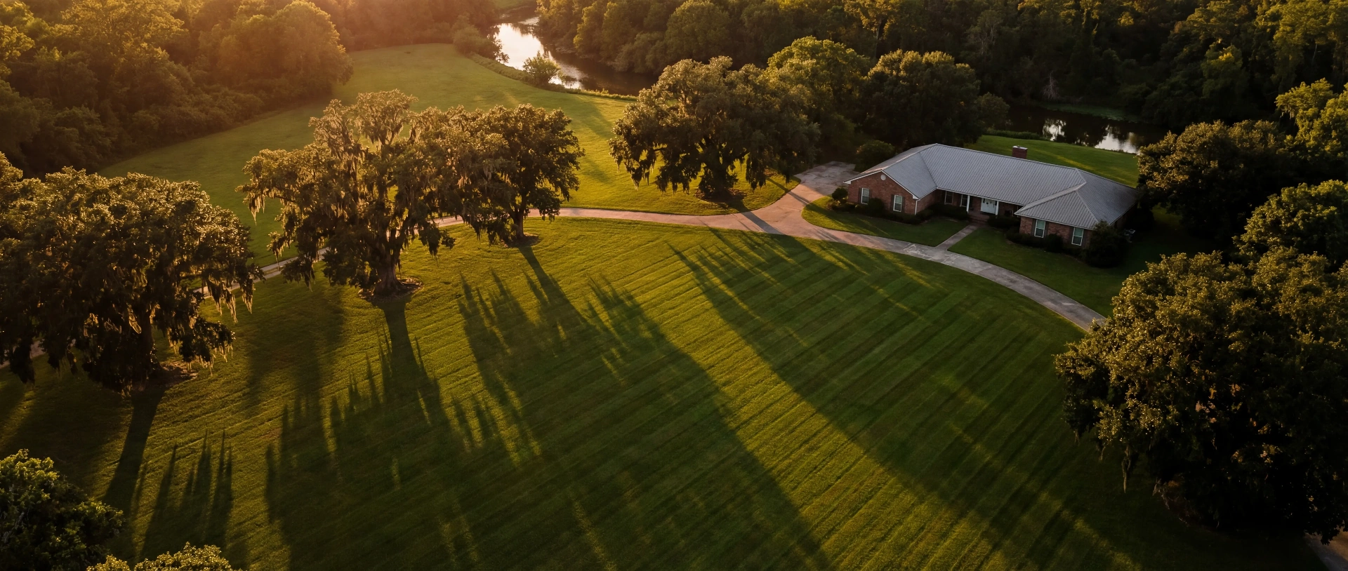 Aerial view of a sprawling Ascension Parish estate at golden hour with a freshly striped lawn